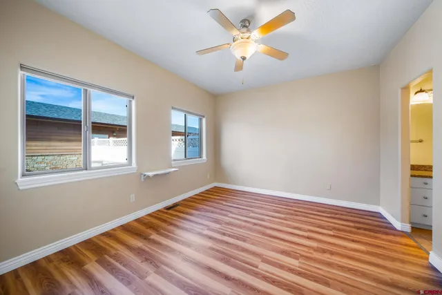 a view of an empty room with a window and wooden floor