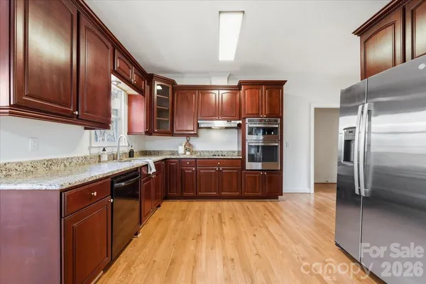 a kitchen with stainless steel appliances granite countertop wooden cabinets a refrigerator and a sink
