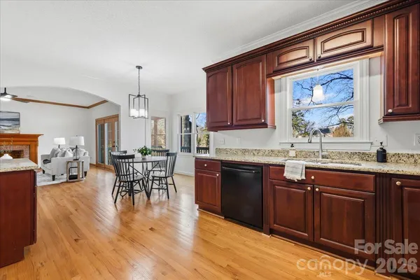 a kitchen with stainless steel appliances granite countertop a stove top oven a sink dishwasher a dining table and chairs with wooden floor
