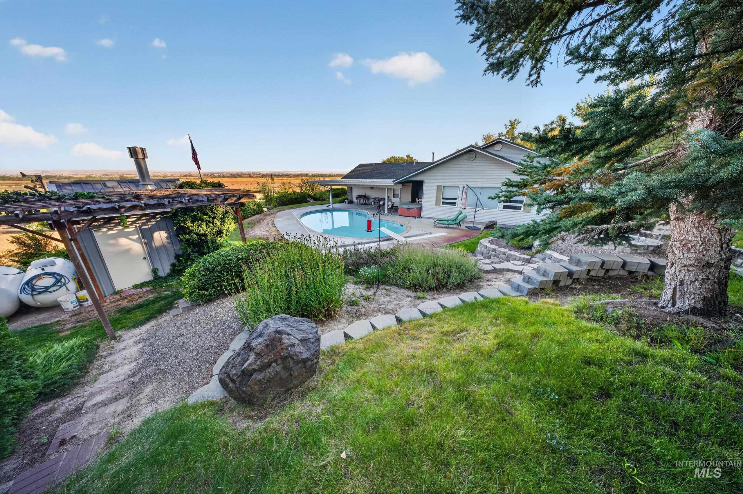 5540 Finley Road Fruitland, ID 83619 - Photo 26 of 50 Exterior featuring a swimming pool, gravel paths, tiered landscaping, and mature trees