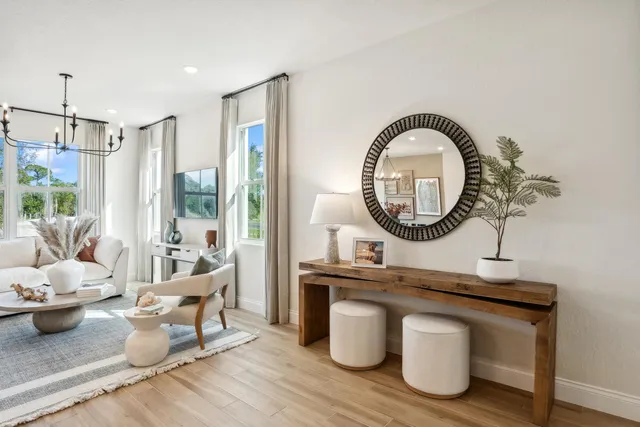 a living room with furniture a mirror a lamp and a large window