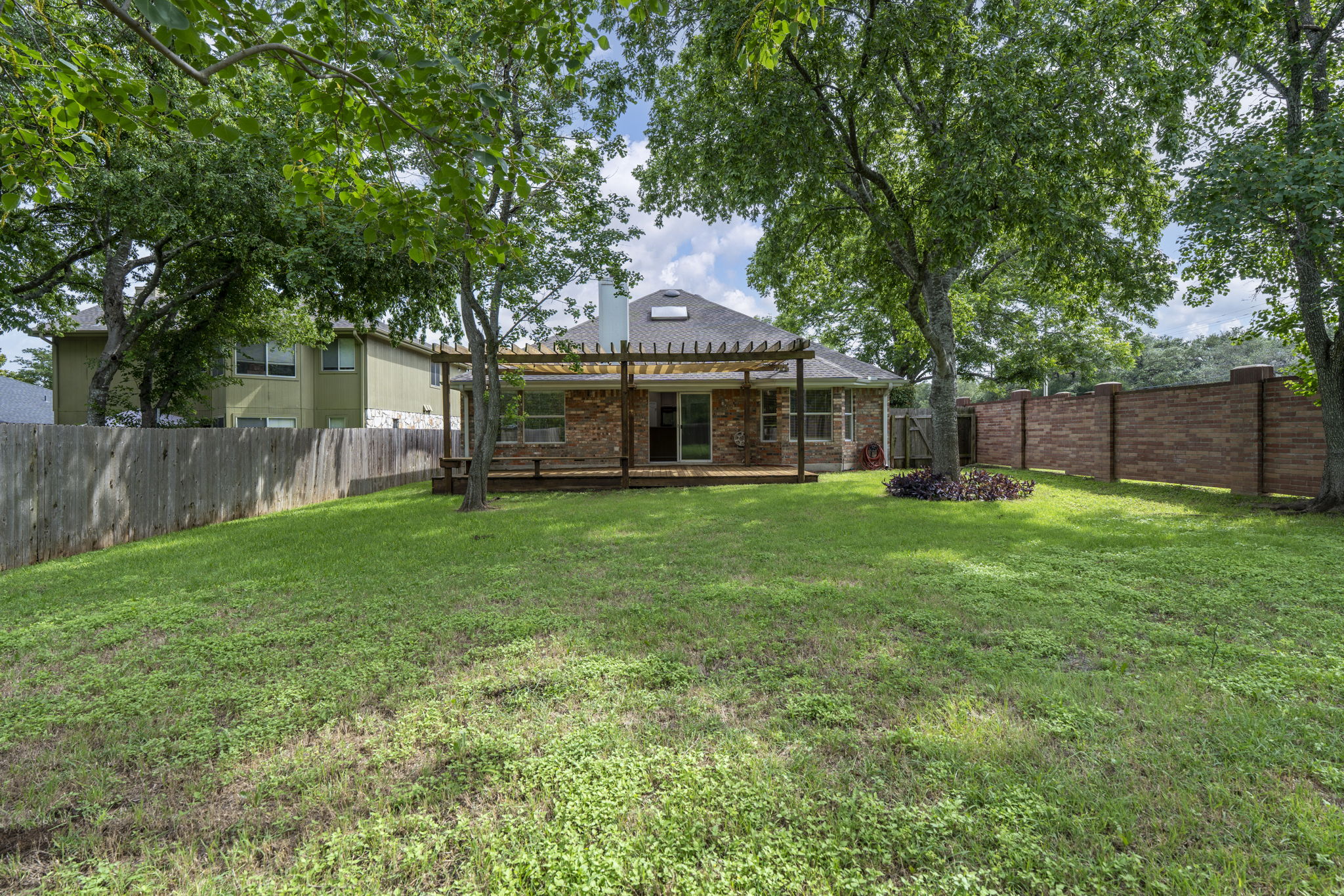 7172 Ridge Oak Road Austin, TX 78749 - Photo 11 of 40 A spacious backyard with mature trees and a pergola-covered deck offers serene outdoor living.
