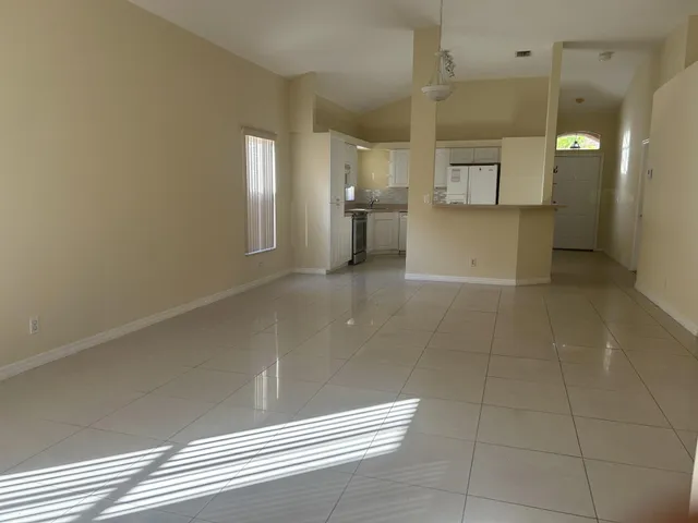 a view of a hallway with wooden floor and a kitchen