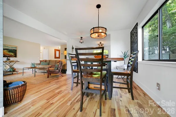 a view of a dining room and livingroom with furniture wooden floor a rug a flat screen tv a rug a fireplace and a chandelier