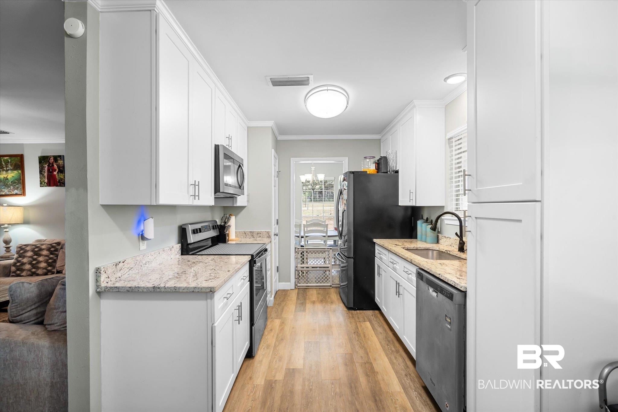 9987 Downing Street Semmes, AL 36575 - Photo 6 of 20 Kitchen with stainless steel appliances, white cabinetry, sink, ornamental molding, and light hardwood / wood-style flooring