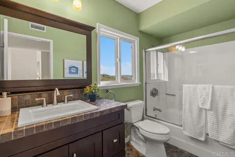 a bedroom with a large bed and a chandelier fan