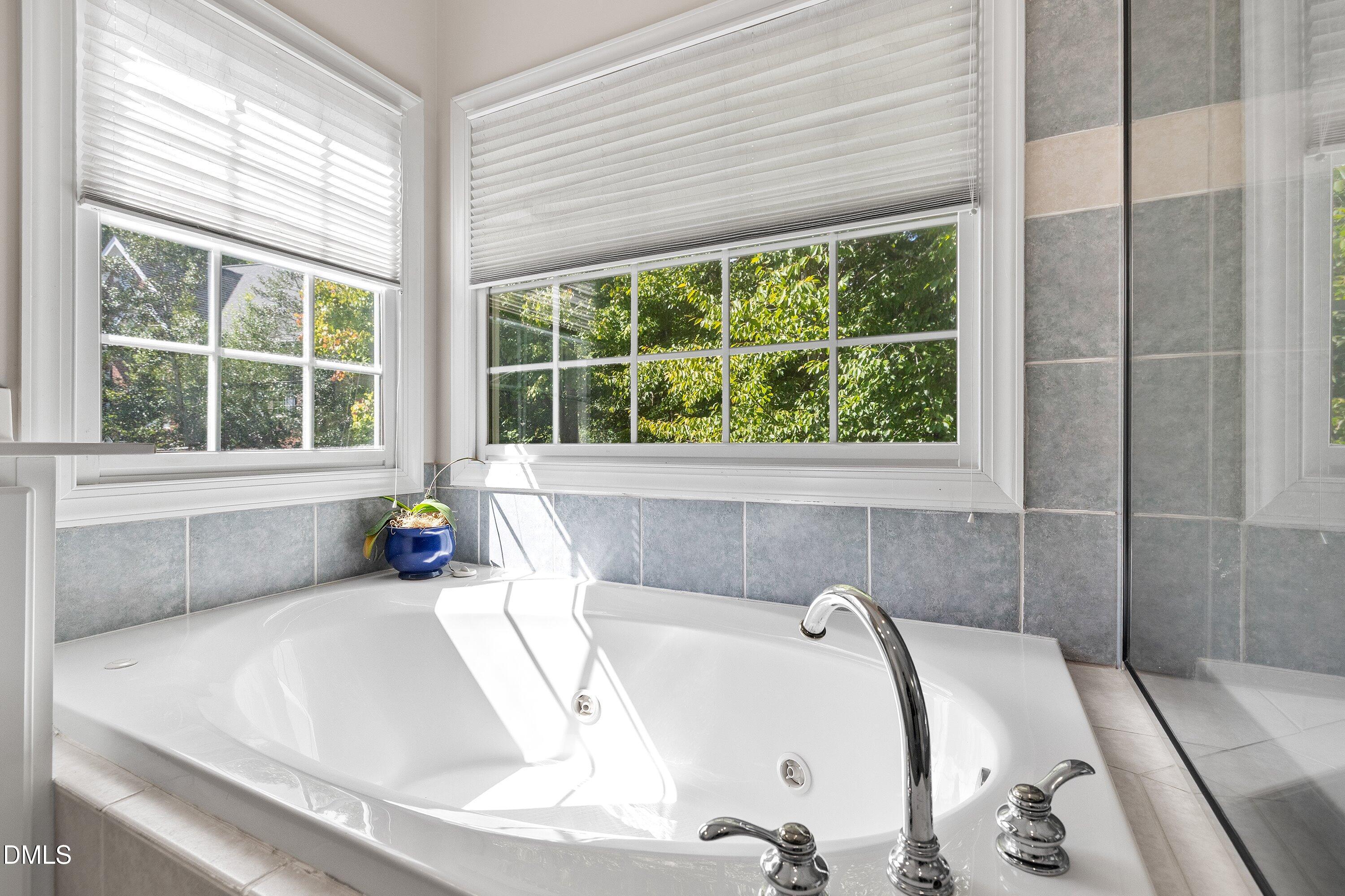 3914 Sterling Ridge Lane Durham, NC 27707 - Photo 37 of 66 White built-in soaking tub with polished chrome fixtures, surrounded by grey square-tiled wainscoting