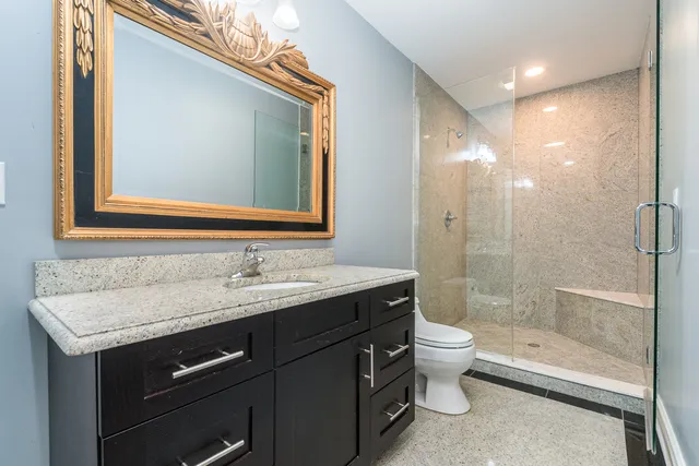 a bathroom with a granite countertop sink toilet and shower