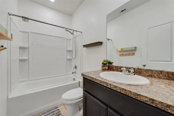 a bathroom with a granite countertop sink a toilet a mirror a bathtub and shower