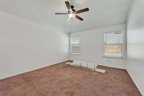 an empty room with windows and fan