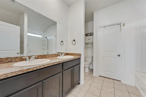 a bathroom with a granite countertop sink a toilet and shower