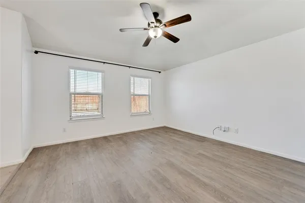 an empty room with windows and fan