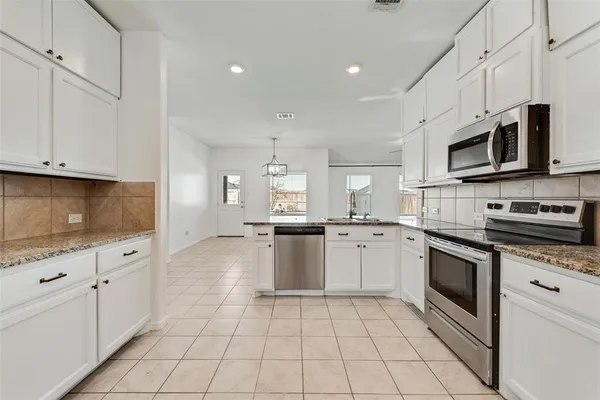 a kitchen with stainless steel appliances granite countertop a sink and dishwasher a stove top oven with white cabinets