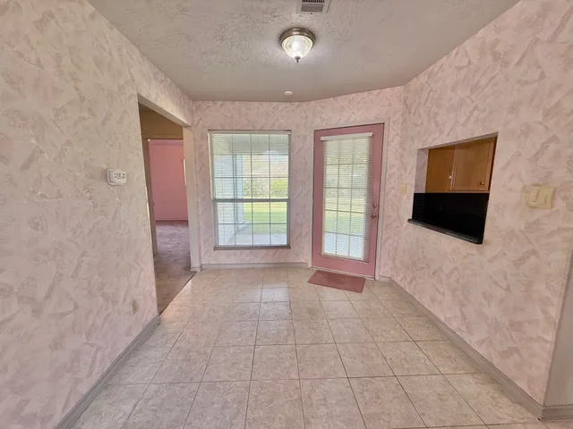 a view of an empty room with a window and a kitchen