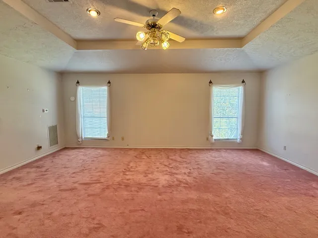 en empty room with windows and chandelier fan