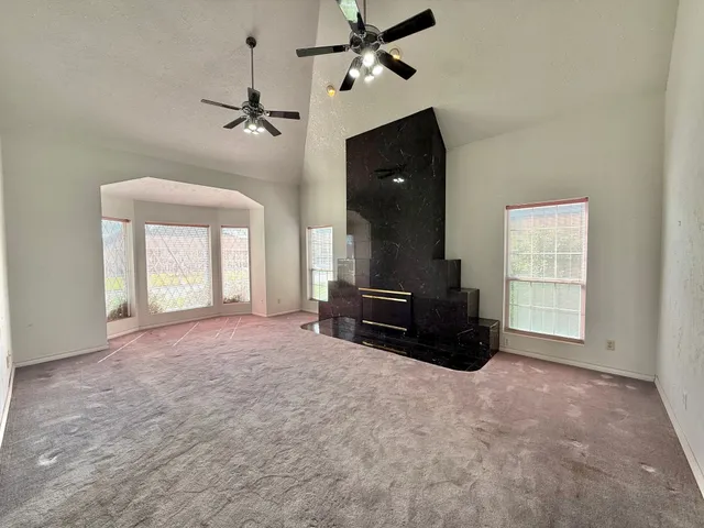 an empty room with windows and ceiling fan