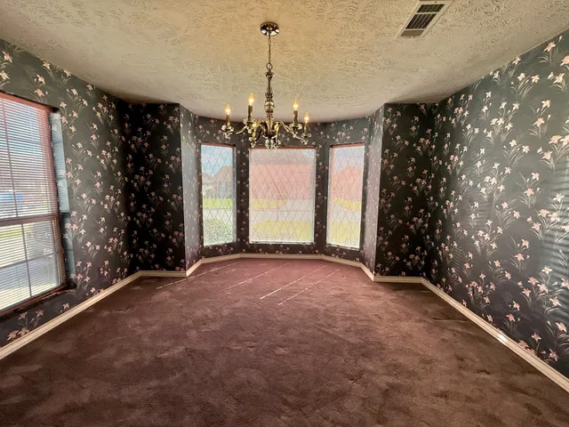 an empty room with windows and ceiling fan