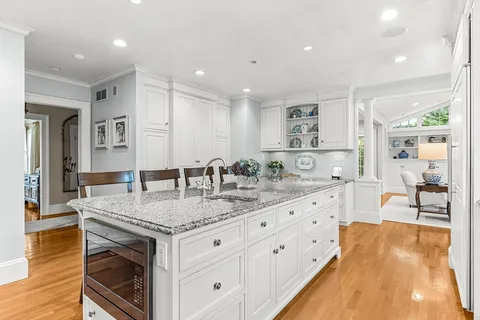 a large kitchen with granite countertop a sink and cabinets with wooden floor