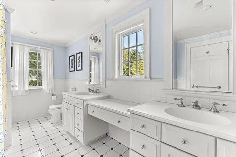 a bathroom with a sink toilet a mirror and window
