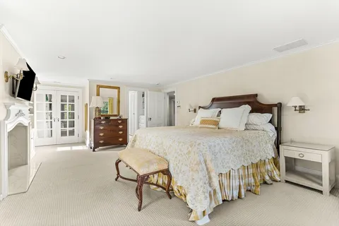 a bedroom with a bed flat screen tv and a fireplace