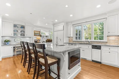a kitchen with stainless steel appliances granite countertop wooden floor a sink a stove a dining table and chairs