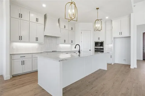 a kitchen with stainless steel appliances granite countertop a sink a stove a refrigerator and white cabinets