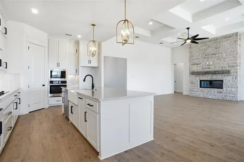 a large white kitchen with kitchen island a stove a sink a refrigerator and a fireplace