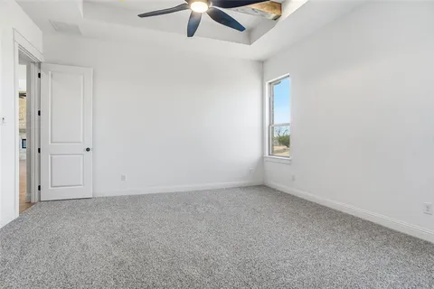 an empty room with a ceiling fan and carpet