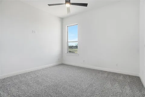 an empty room with a ceiling fan and window
