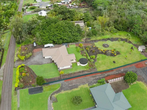 an aerial view of a tennis ground and a cars park side of the road