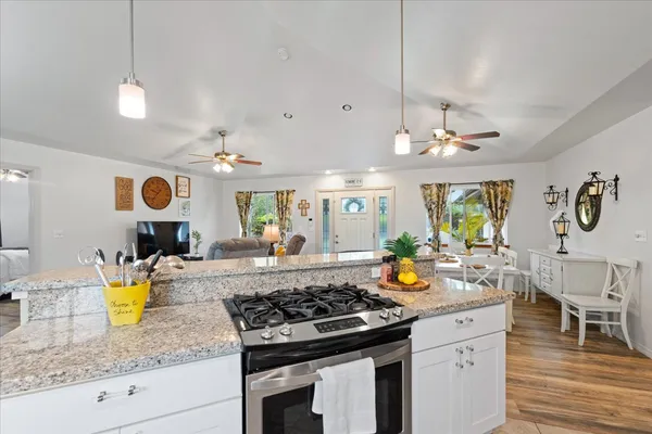 a kitchen with a stove a oven a dining table and chairs with wooden floor