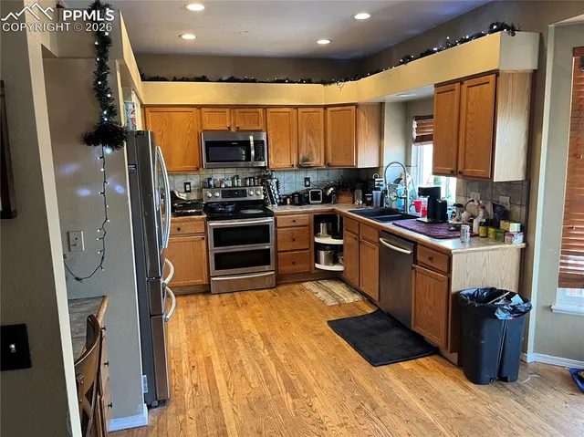 a kitchen with stainless steel appliances granite countertop a refrigerator a sink dishwasher a stove and white cabinets with wooden floor