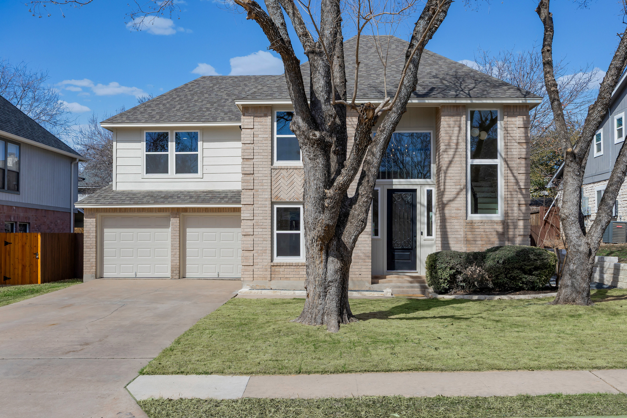 View of front of house featuring a shingled roof, a garage, driveway, and brick siding
