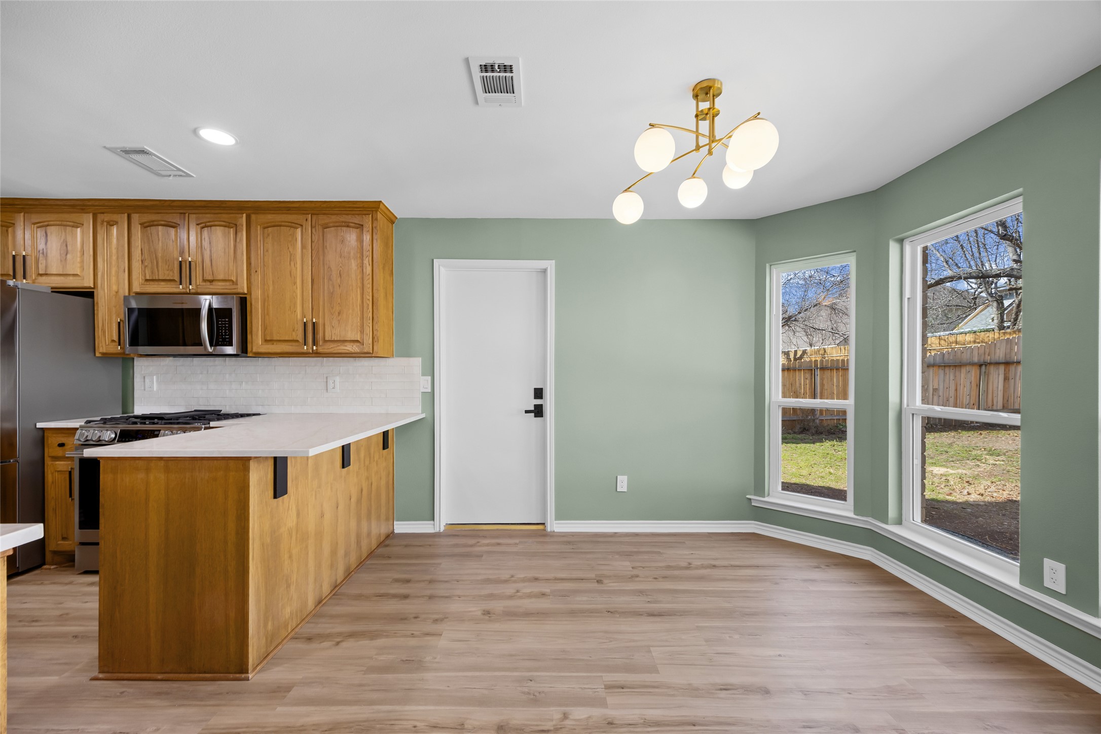 1002 Crestview Street Round Rock, TX 78681 - Photo 11 of 40 Kitchen with stainless steel appliances, suspended lighting, wood finish cabinets, light wood-style floors, and a breakfast bar area