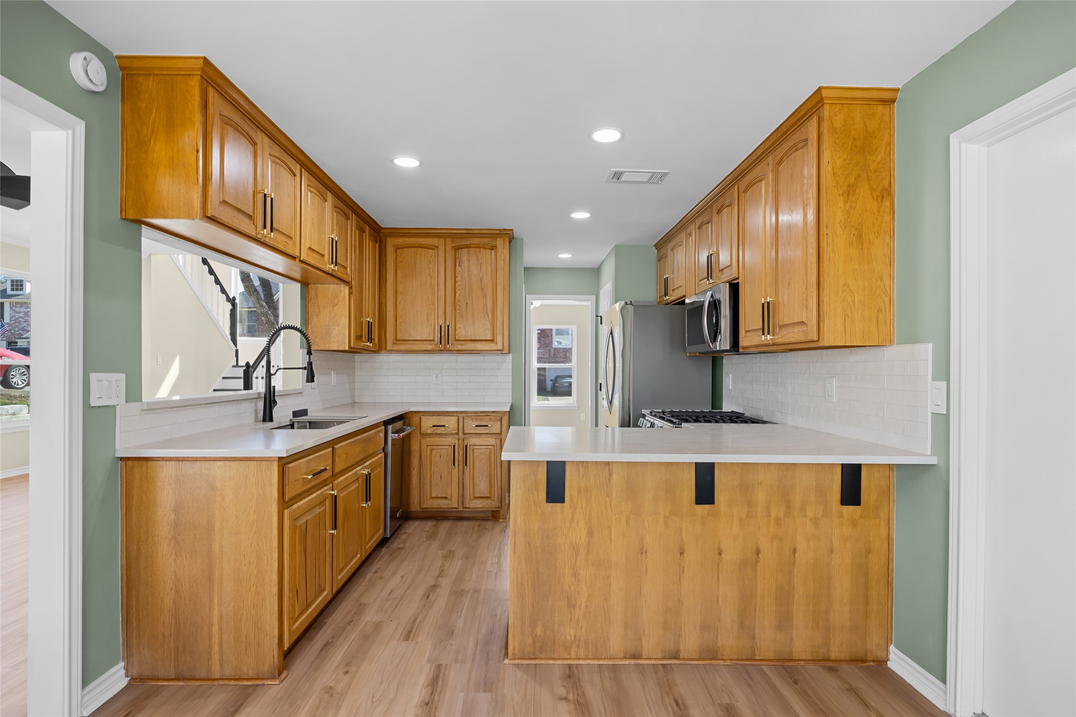 1002 Crestview Street Round Rock, TX 78681 - Photo 13 of 40 Kitchen featuring wood finish cabinetry, a peninsula, light wood-style floors, plenty of natural light, and recessed lighting