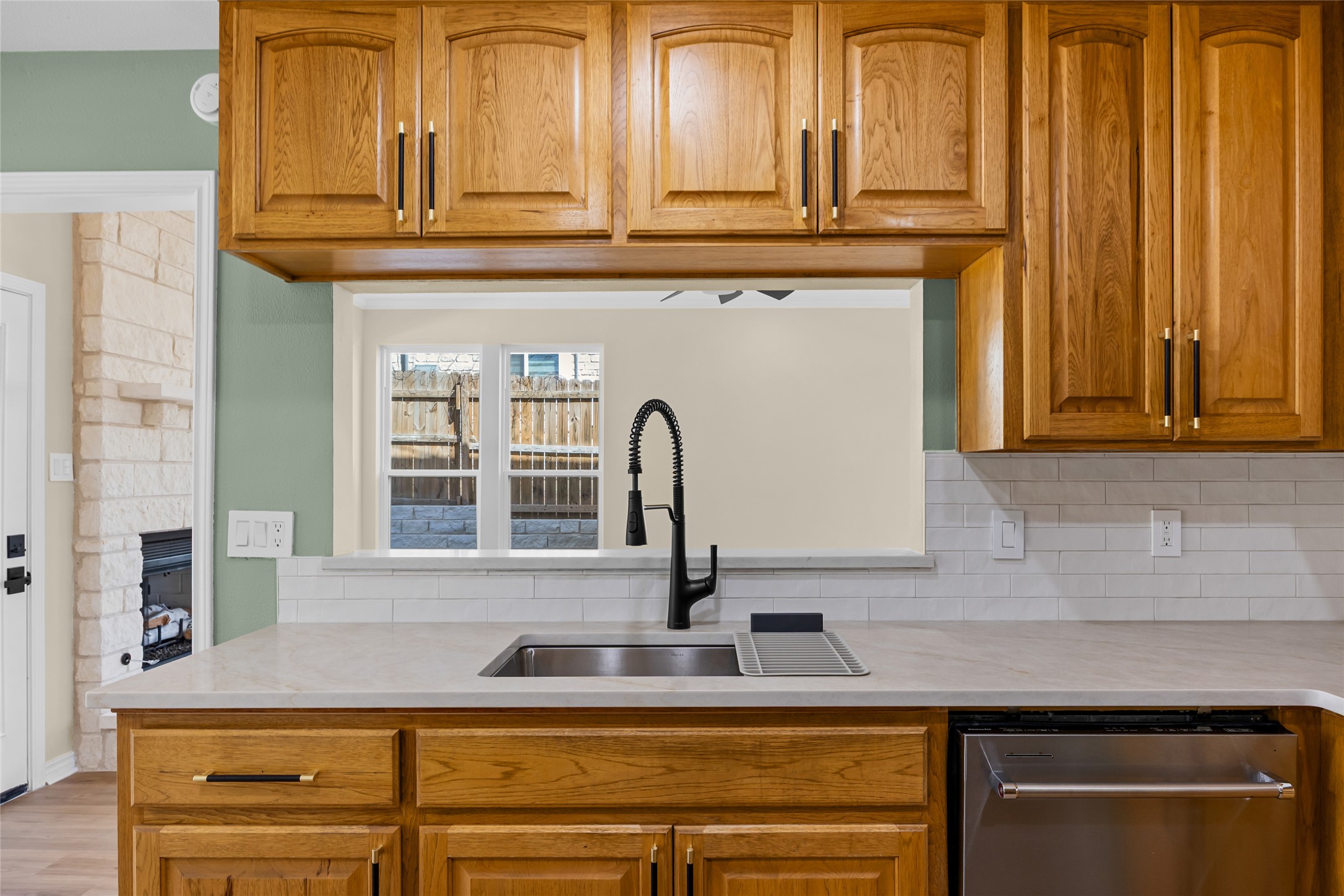 1002 Crestview Street Round Rock, TX 78681 - Photo 15 of 40 Kitchen with wood finish cabinetry, stainless steel dishwasher, a fireplace, and tasteful backsplash