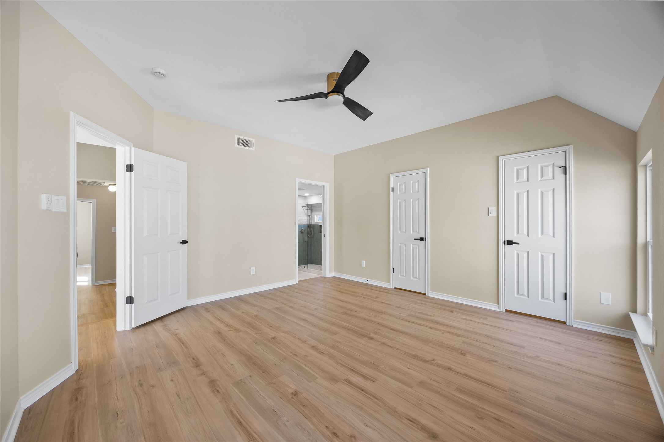 1002 Crestview Street Round Rock, TX 78681 - Photo 22 of 40 Unfurnished bedroom with light wood-style flooring, ceiling fan, connected bathroom, vaulted ceiling, and multiple closets