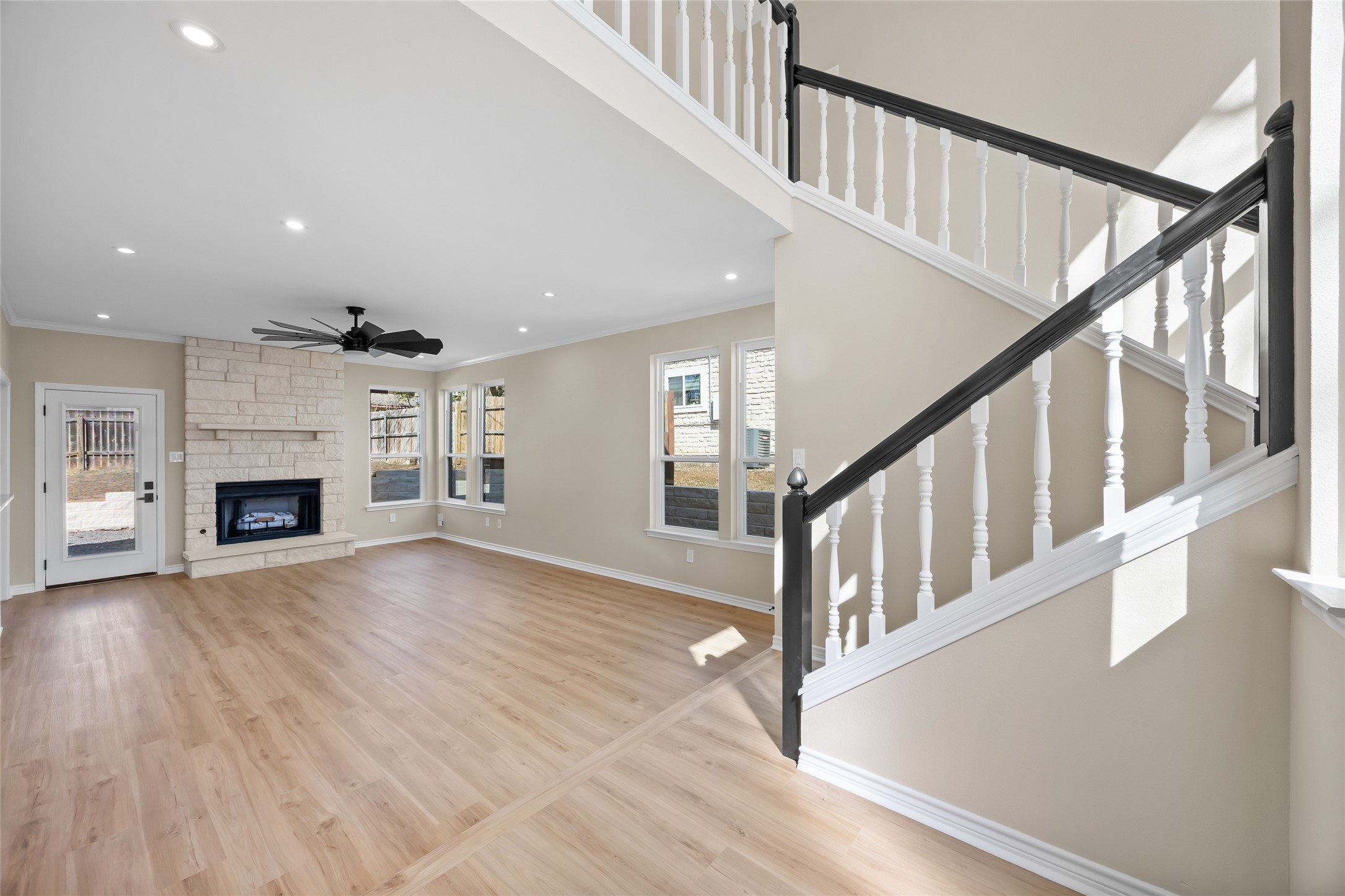 1002 Crestview Street Round Rock, TX 78681 - Photo 4 of 40 Unfurnished living room with a stone fireplace, light wood finished floors, recessed lighting, a ceiling fan, and crown molding