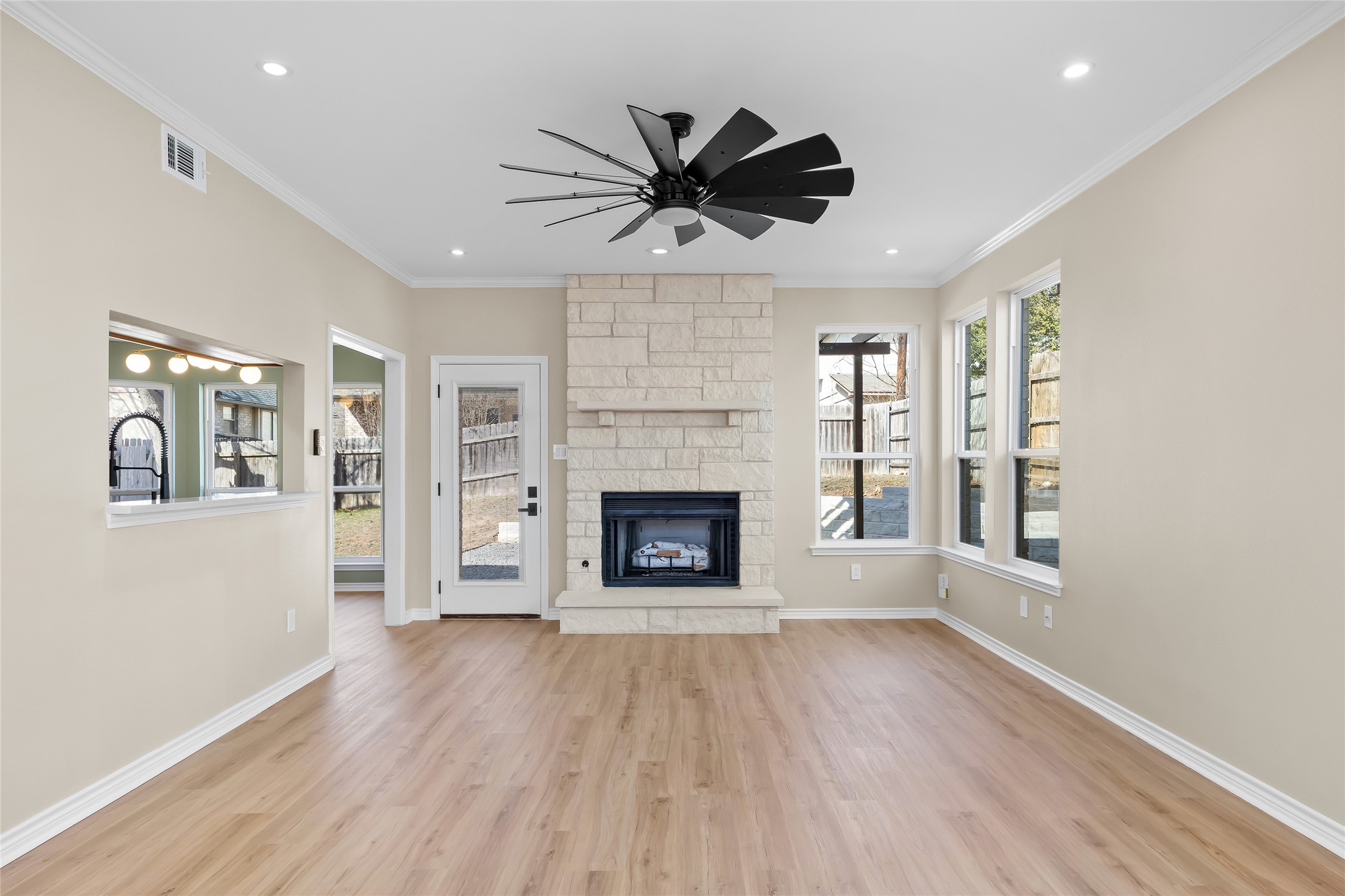 1002 Crestview Street Round Rock, TX 78681 - Photo 5 of 40 Unfurnished living room with a stone fireplace, light wood-style flooring, a ceiling fan, recessed lighting, and crown molding