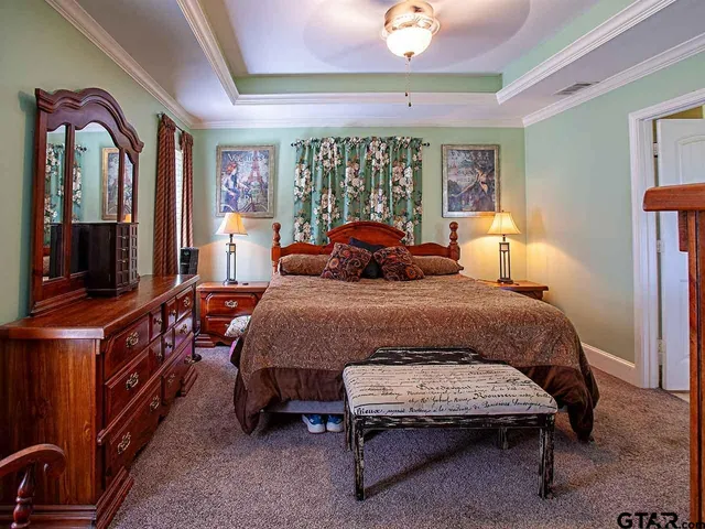 a bedroom with a bed a mirror on dresser and a window