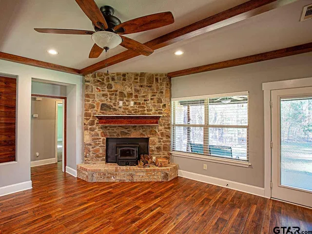 a view of an empty room with wooden floor fireplace and a window