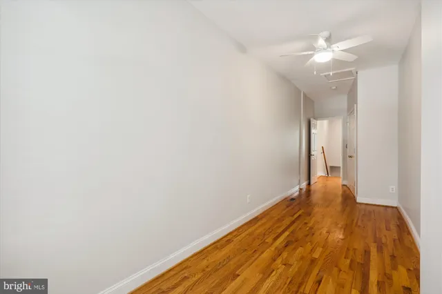 a view of a room with wooden floor and a ceiling fan