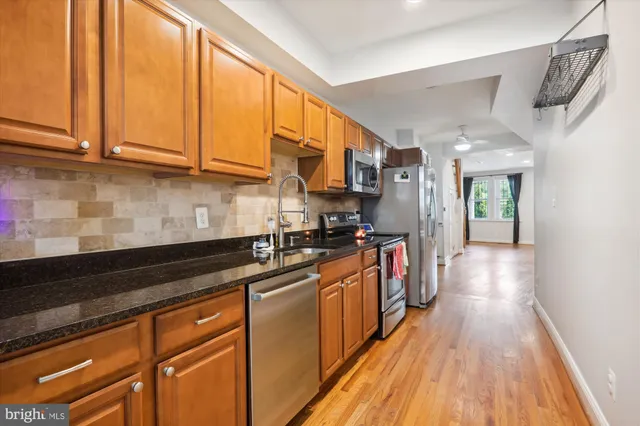 a kitchen with stainless steel appliances granite countertop a sink and wooden cabinets