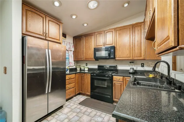 a kitchen with stainless steel appliances granite countertop a refrigerator a stove top oven and sink