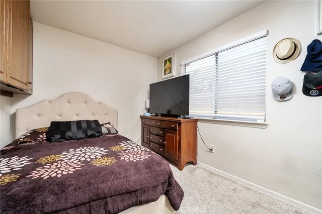 a bedroom with a bed and flat tv screen on the dresser