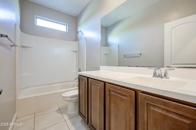 a bathroom with a granite countertop sink a toilet a mirror and bathtub