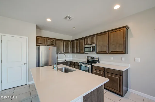 a kitchen with stainless steel appliances a refrigerator a sink a stove a microwave and island