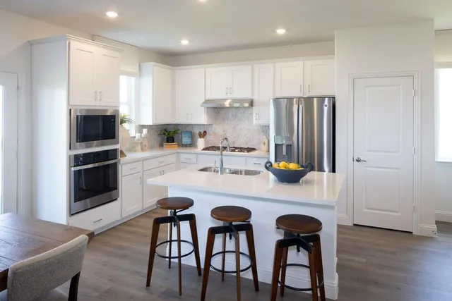 a kitchen with a dining table chairs refrigerator and cabinets