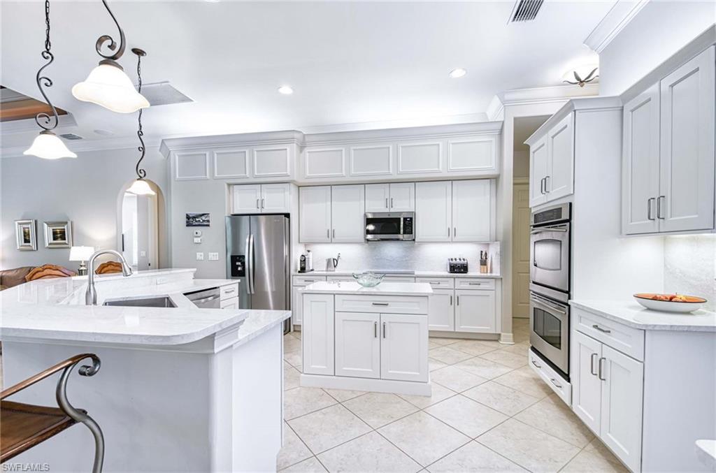 3002 Crayton Road Naples, FL 34103 - Photo 9 of 27 a kitchen with kitchen island white cabinets and refrigerator
