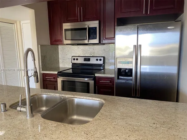 a kitchen with granite countertop a refrigerator and a stove top oven